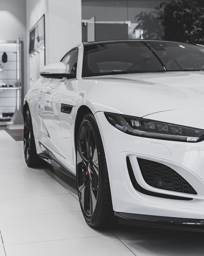 Close-up of a white sports car's front end in a modern showroom, showcasing sleek design and elegance.